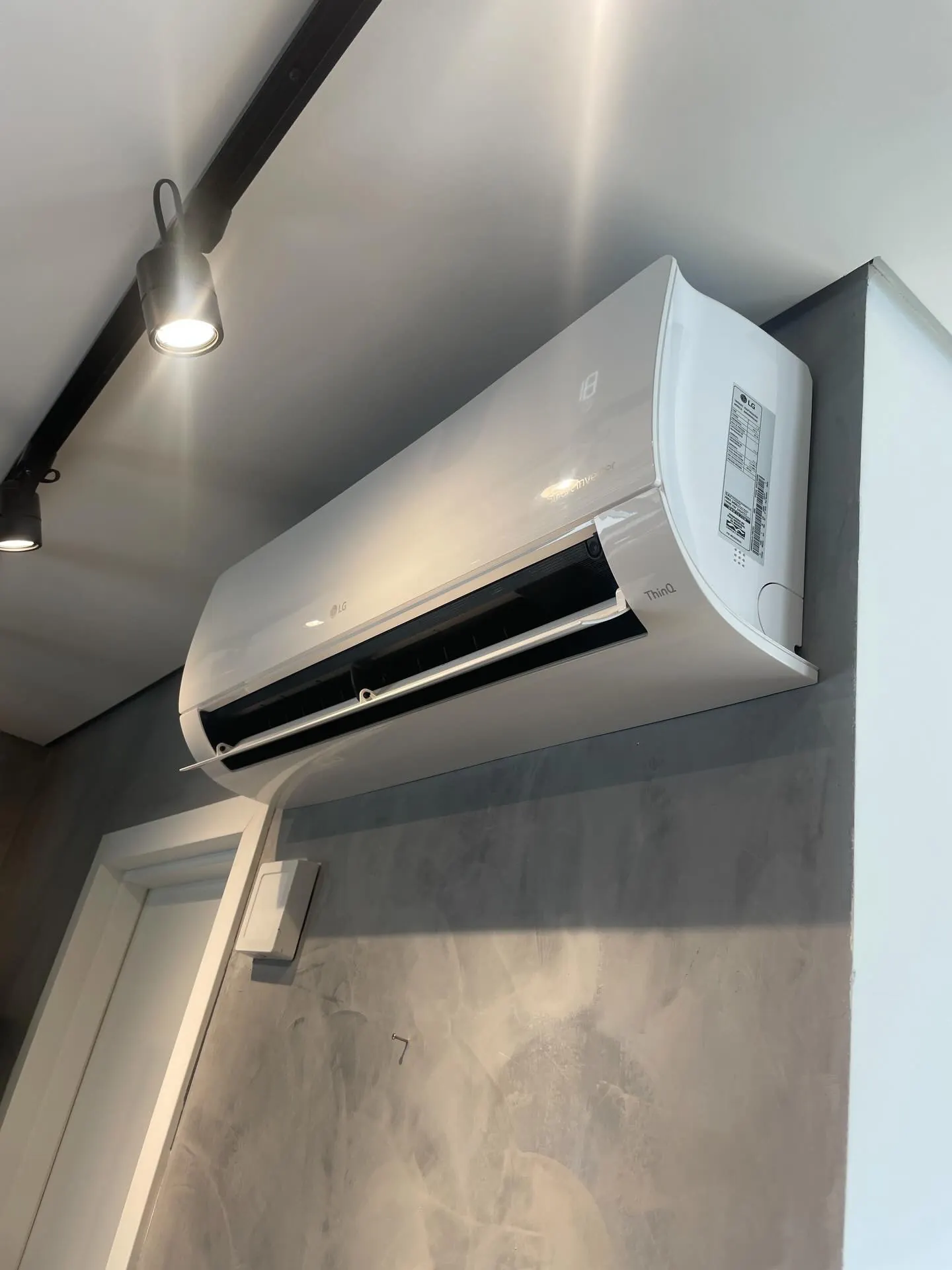 Split LG de um bi split instalado pela Tune numa parede de cimento queimado, com spots no teto