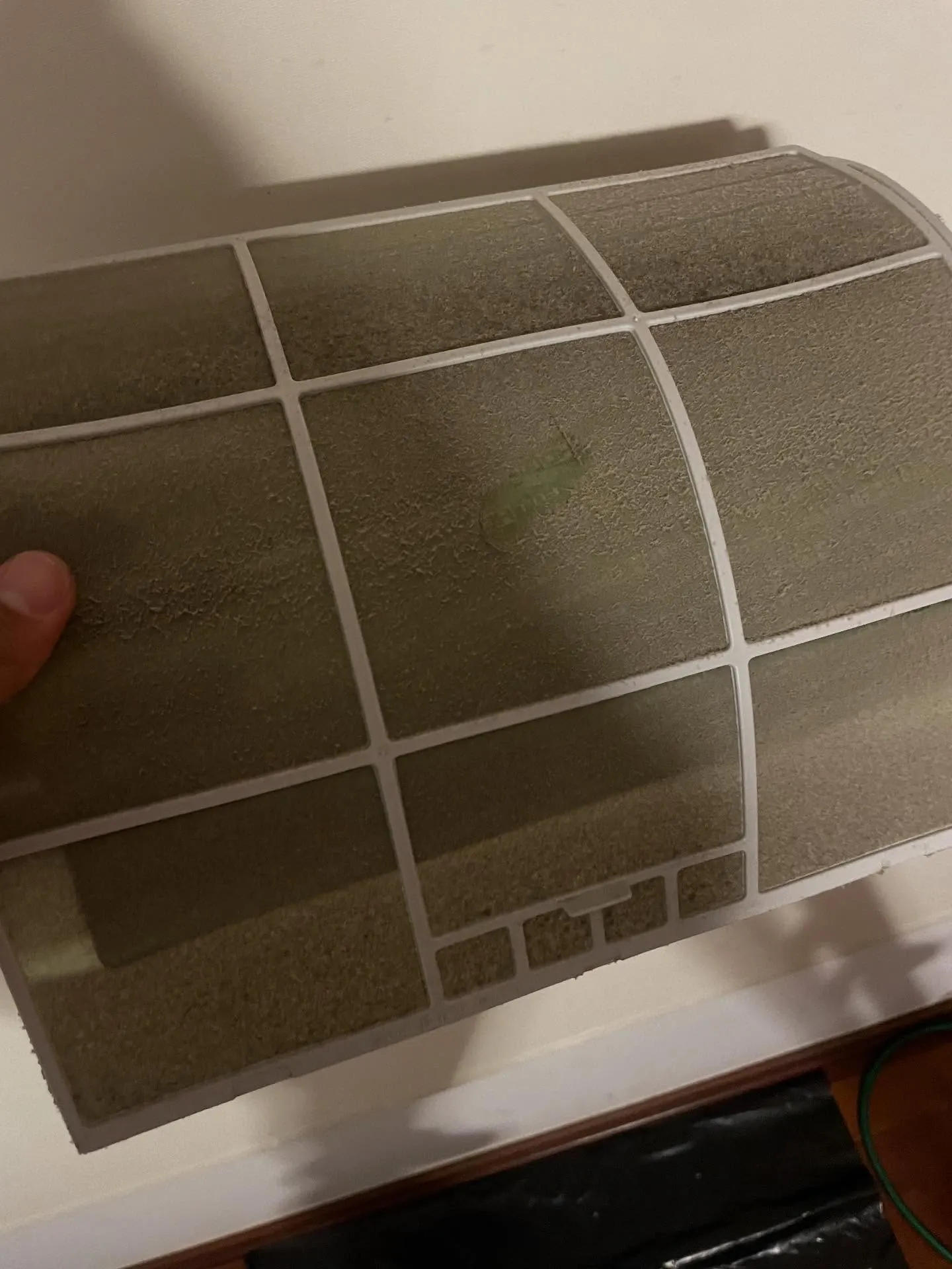 Filtro de ar de um split Samsung coberto de poeira, retirado na manutenção preventiva